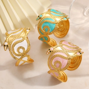 Detail of three snake-shaped enamel bracelets in white, pink, and blue with gold plating