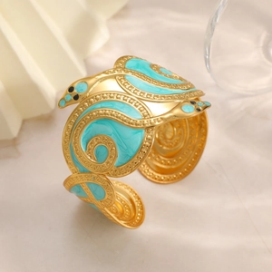 Close-up of golden snake bracelet with turquoise enamel details and bead textures