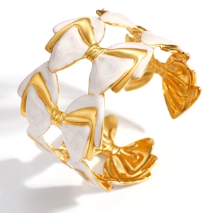 Détail d'un bracelet ouvert doré avec nœuds en émail blanc et design ajouré