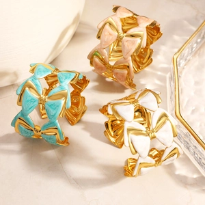 Détail des charms nœuds en émail coloré sur un bracelet jonc réglable plaqué or