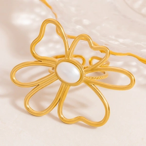 Golden open ring featuring an intricate hollow floral design with an oval white stone