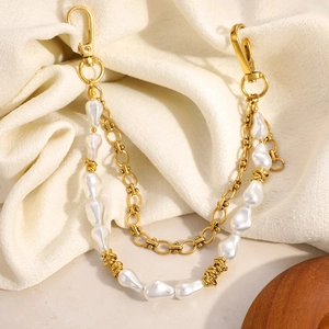 Detail of 18K gold plated heart chain with baroque pearls on cream fabric background