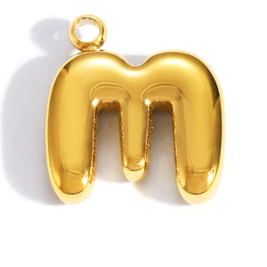 Dettaglio macro del ciondolo con lettera M 3D dorata e finitura lucida