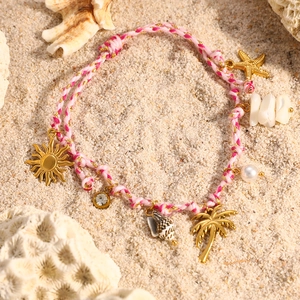 Pulsera bohemia estilo océano con concha rosa y estrella de mar dorada en la arena