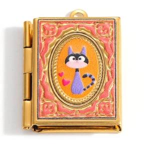 Detail of a book-shaped locket featuring a cartoon cat painting and floral patterns