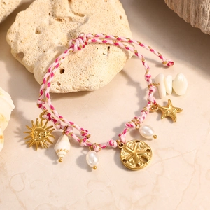 Primer plano de la pulsera tejida estilo océano con conchas marinas y dijes de estrella