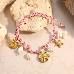 Detalle de pulsera trenzada de tema marino con dijes de estrella de mar en oro 18K