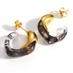 Detalle de pendientes en C bañados en oro de 18K con resina marmoleada en blanco y negro