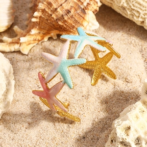 Détail du bracelet en acier inoxydable 18K avec étoiles de mer colorées sur sable