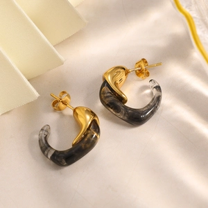 Detalle de pendientes en C bañados en oro de 18K con resina marmoleada y sombras elegantes