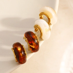 Close-up of vintage resin C-shape earrings hanging on a white ceramic dish