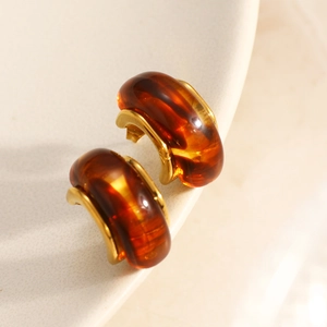 Macro detail of amber resin C-shape earrings with 18K gold plated base on ceramic