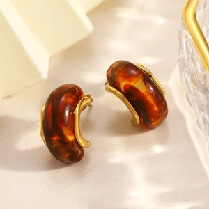 Detailed view of C-shaped resin earrings with amber tortoiseshell and gold-plated accents