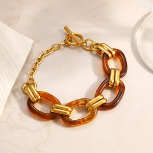 Elegant amber resin oval link bracelet with 18K gold plated clasp on marble background