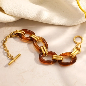 Detail of amber resin links and gold metal rings with toggle clasp on a stone surface