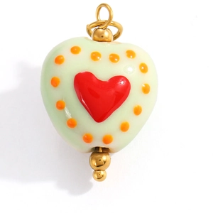 Detail of light green enamel heart charm with red heart pattern and golden metal loops
