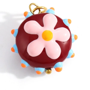 Macro detail of colorful enamel mushroom flower pendant with gold metal ring attachment