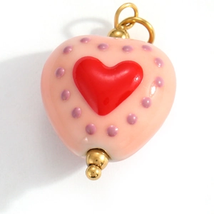 Macro shot of heart-shaped stainless steel pendant with pink enamel and red center