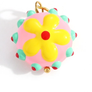 Close-up of pink floral spherical pendant with yellow flower and gold metal bead