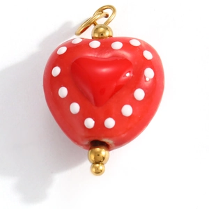Macro view of a red heart-shaped pendant with white polka dots and gold beads