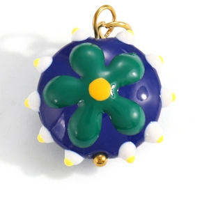 Detail of colorful blue sphere pendant with green flower and enamel flower elements
