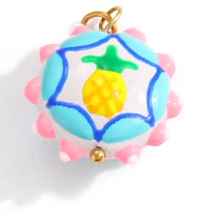 Detail of a round pineapple pendant with colorful resin and golden metal loop