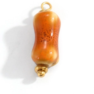 Detail showing orange ceramic column pendant with golden metal caps and textured glaze