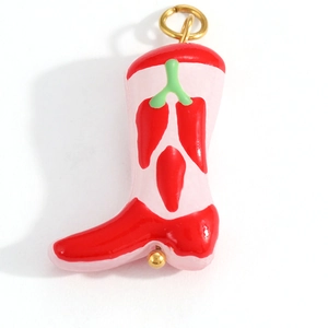 Detail of pink cowboy boot pendant with red chili patterns and gold ring attachment