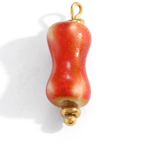 Detailed macro view of orange handmade ceramic gourd pendant with gold metal ring hook