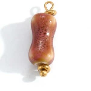 Macro detail of a peanut-shaped ceramic pendant with mottled glaze and gold metal loops