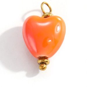 Detailed macro view of orange heart-shaped enamel pendant with golden loop attachment