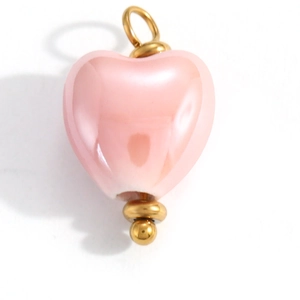 Macro shot of pale pink heart-shaped pendant with polished gold metal hardware and finish