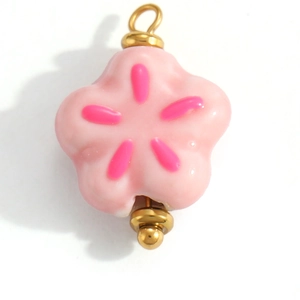 Detailed view of pink five-petal flower pendant with gold metal caps and hanging ring