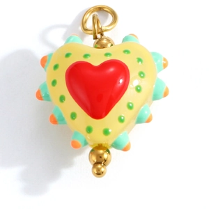 Macro detail of heart-shaped yellow pendant with red heart and colorful enamel dots