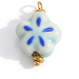 Detailed macro view of a handmade light blue ceramic flower charm with golden metal loop