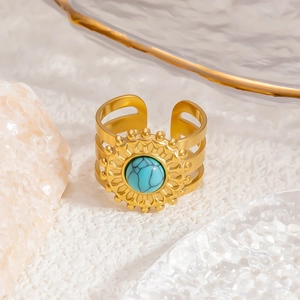 Macro detail of vintage gold stainless steel ring with turquoise stone inlay and sunburst frame