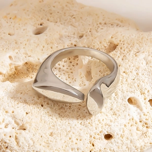 Makroaufnahme eines silbernen asymmetrischen Rings auf einem Natursteinsockel