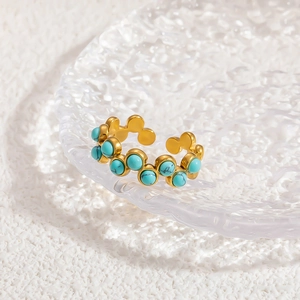 Gros plan détaillé d'une bague ondulée dorée sertie de turquoises sur un plateau