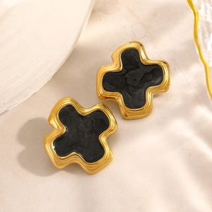 Boucles d'oreilles croix plaquées or 18 carats avec résine noire sur fond de marbre
