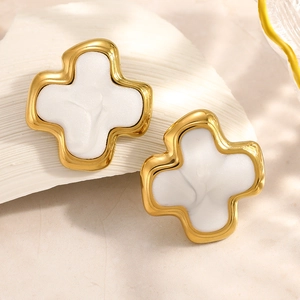 Détail de boucles d'oreilles croix dorées avec texture de marbre blanc sur socle en pierre