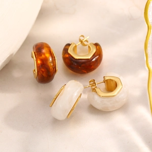 Dettaglio di orecchini a cerchio in resina a forma di C con texture ambra e marmo e oro 18K