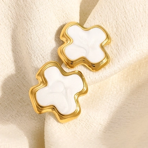 Vue détaillée de boucles d'oreilles dorées 18K avec incrustation blanche sur tissu texturé