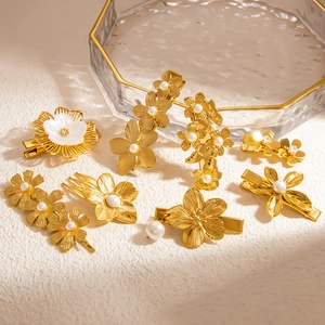 Elegant gold flower hair clips set with pearls and shell textures on glass tray