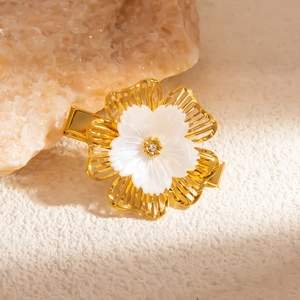 Elegant gold flower hair clip with pearls and rhinestones on a natural stone background
