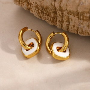 Vue détaillée de boucles d'oreilles carrées plaquées or 18K avec émail blanc sur socle