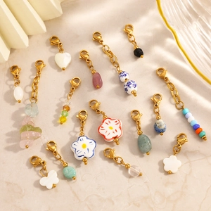 Detailed close-up of various gold stainless steel charms with natural stones and shell beads