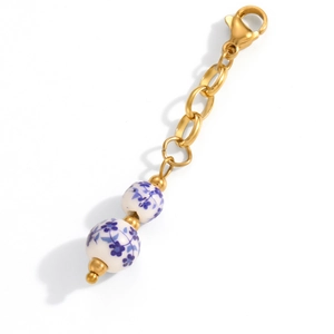 Detail of blue and white ceramic beads and gold lobster clasp on stainless steel necklace