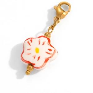 Close-up of handmade white floral ceramic pendant with red patterns and gold lobster clasp