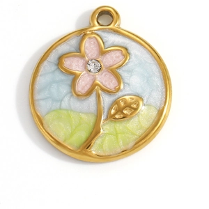Détail du pendentif doré circulaire avec paysage fleuri coloré et petit strass brillant