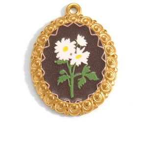 Macro view of a gold oval pendant featuring a white daisy design on a dark base